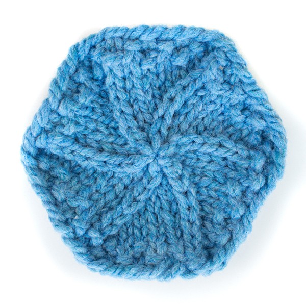 Knitting Hook Piercing a Round Teal Crocheted Coaster Stock Image