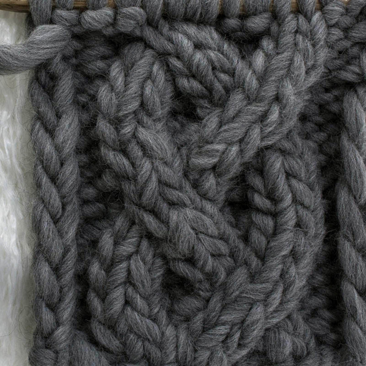 braided cable knit stitch swatch on a faux fur rug