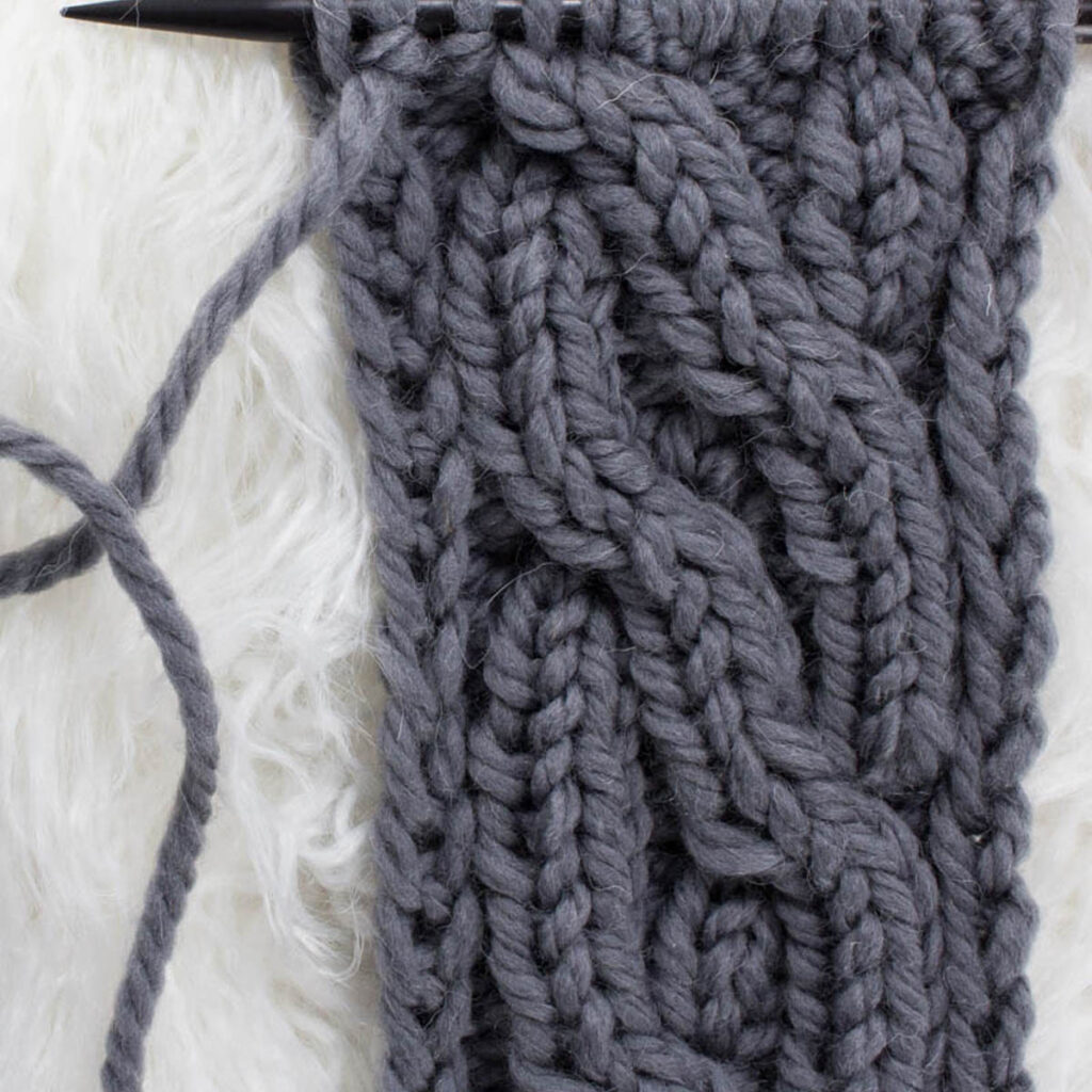 Swatch of the Crossing Pathways Cable Knit Stitch on a fur blanket.