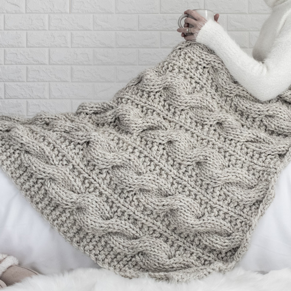 Knitting needles on gray knitted blanket from merino wool, super