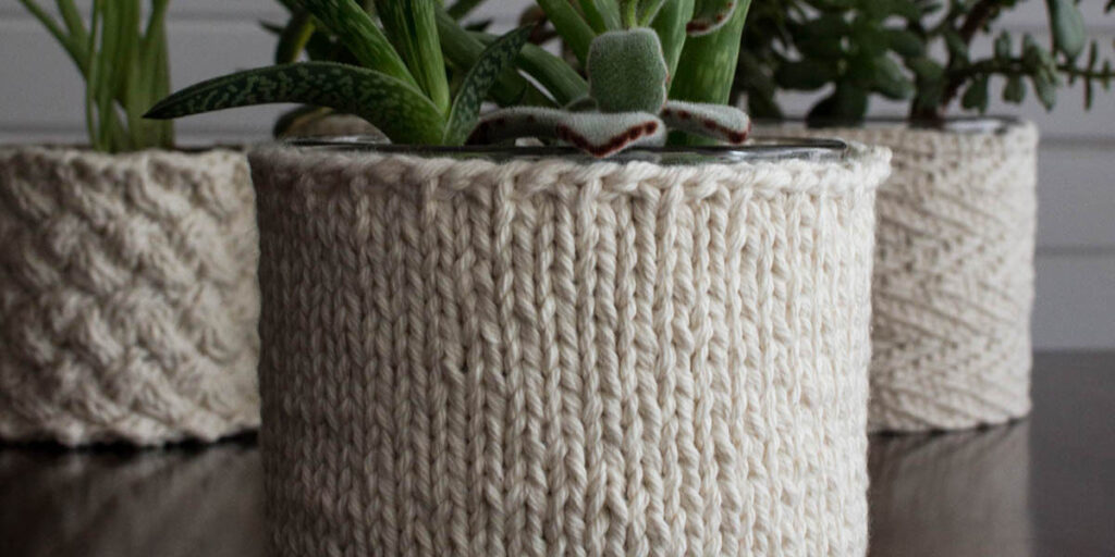pic of a beginner stockinette stitch knitted plant pot holder covering a pot with a plant in it