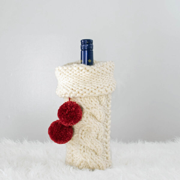 Christmas cable knitted wine bottle cover displayed on a wine bottle.