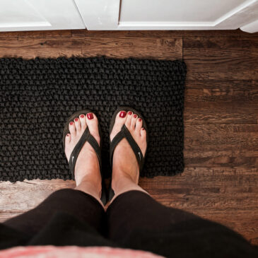 top down photo of women's feet on a t-shirt yarn rug