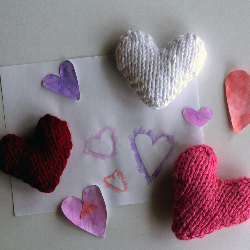 2 heart pillows on a craft table with hand painted hearts