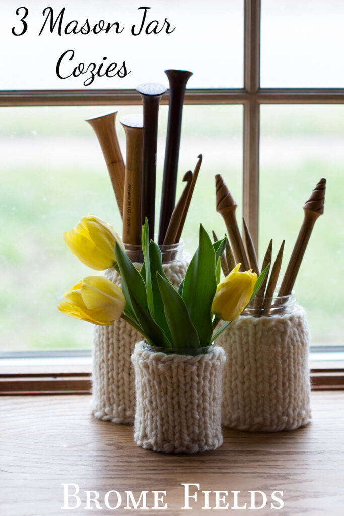 3 Mason Jar Cozies displayed on a mason jars with tulips & wooden knitting needles