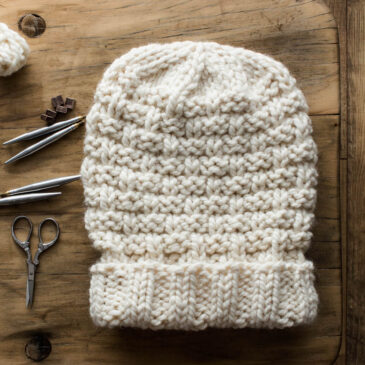 Slouchy Chunky knitted Hat displayed on a chair with knitting tools