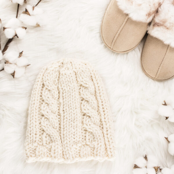 winter knit hat displayed on faux fur blanket with slippers