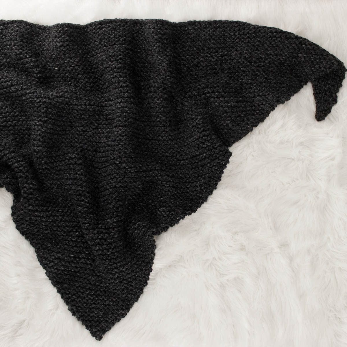 chunky knitted shawl laying on a faux fur blanket